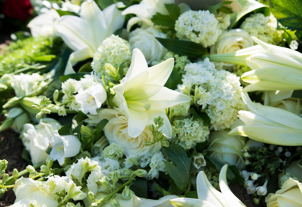 White lilies, roses, and hydrangeas arranged in a serene sympathy floral display