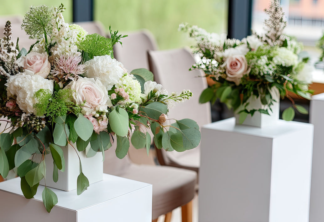 Luxury white and green flower arrangements with roses and hydrangea displayed on modern pedestals