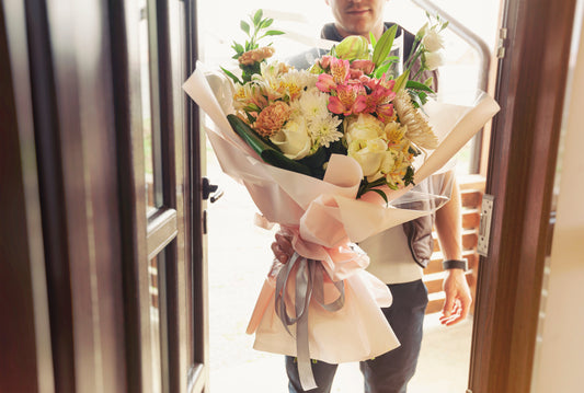 Man delivering fresh mixed flower bouquet at front door, professional local flower delivery service in Washington DC