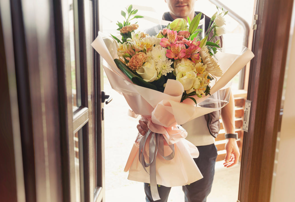 Man delivering fresh mixed flower bouquet at front door, professional local flower delivery service in Washington DC