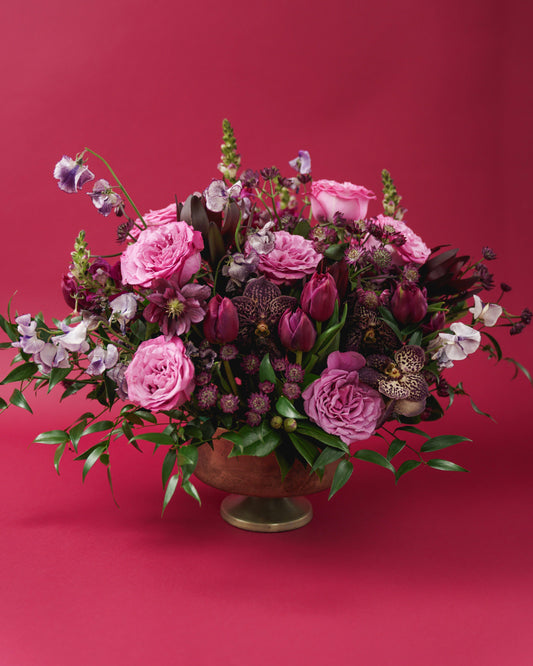 A romantic blend of soft pinks and rich berry tones creates a timeless expression of love. Nicole is an elegant, garden-style arrangement featuring lush roses, tulips, orchids, sweet peas, and seasonal blooms.